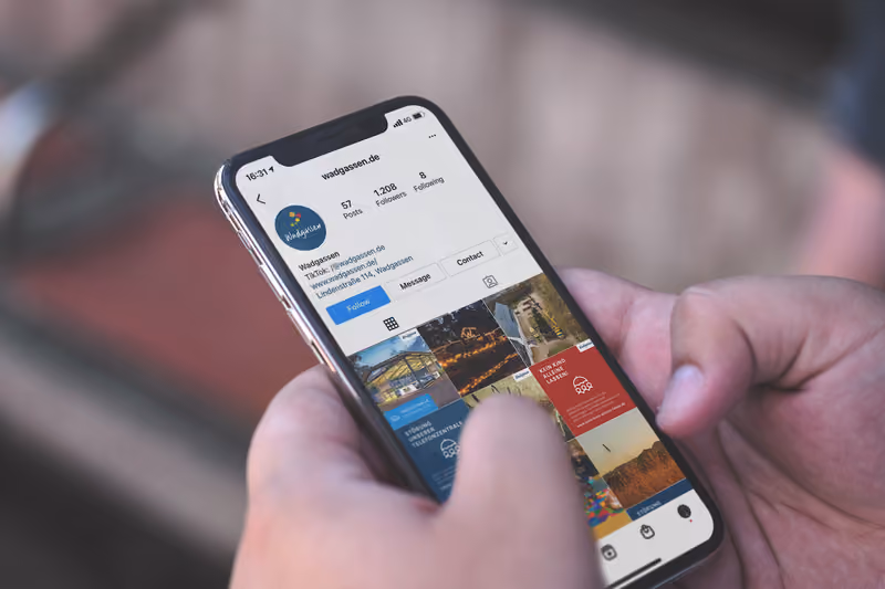 Eine Hand hält ein Smartphone mit dem Instagram-Profil der Gemeinde Wadgassen, in dem die gestalteten Beiträge als Raster zu sehen sind